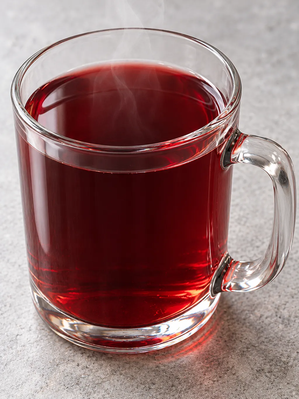 Heiße Feuerzangenbowle mit dunkelroten Reflexen in einer klaren Glastasse